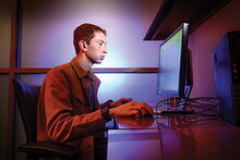 Researcher in blue-lit room in front of a computer