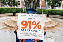 LAS graduate in blue cap and gown holding newspaper with the phrase "91% of LAS alumni secure first destination soon after graduation" across front page