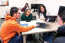 Students in the Econometrics Data Lab gathered around laptops with professor Daniela Alonso Fontes.