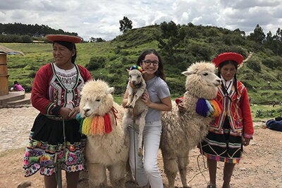 cynthia posing with local people and alpacas
