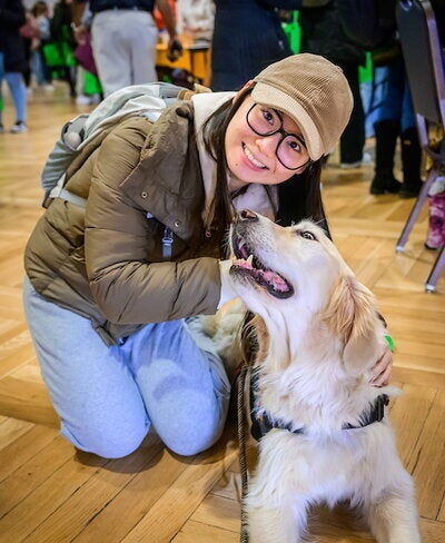 student posing while petting therapy dog