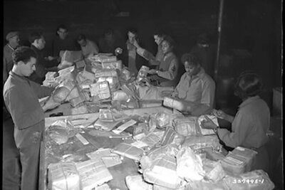 The 6888th sort packages, taken from the mail sacks by French civilian employees, at the 17th Base Post Office in Paris, France. 