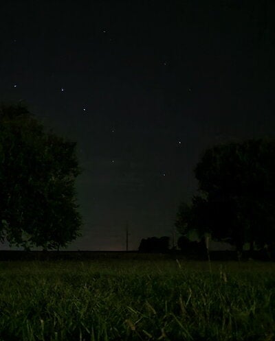 Stars visible in the night sky; view from a field. 