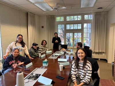 People sitting at a conference table in Coble Hall, gathering for QazTalk.