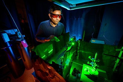 Researcher wearing protective glasses while using a laser to activate an specialized electrochemical reaction inside of an reaction cell.