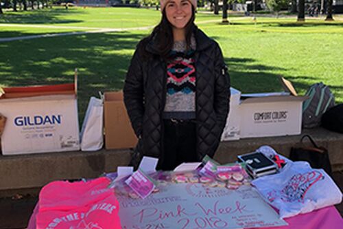 Allison Garetto standing behind a fundraising table on the Quad