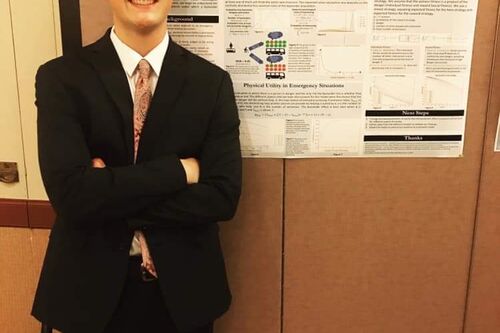 AJ Ingram poses in front of undergraduate research poster