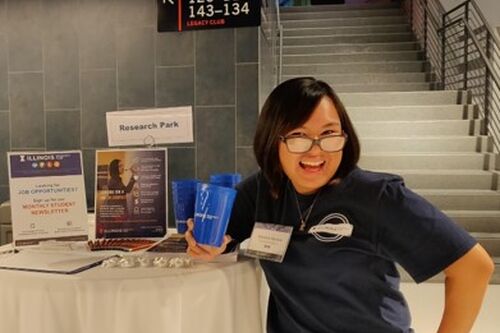 LAS junior Cherish Recera poses for a photo in front of a Research Park promotional table at the State Farm Center