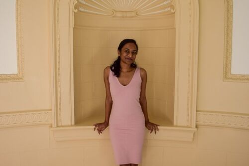 LAS student poses for a photo in a pink dress against a white wall