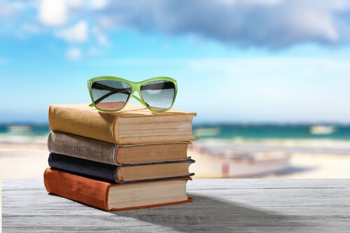A stack of books on a picnic table next to the beach