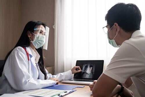 Doctor and patient in masks discuss health issues