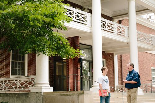 A student talks to a professor outside the English Building