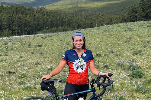 Zona with her bike on a green landscape in front of the Bighorn mountains