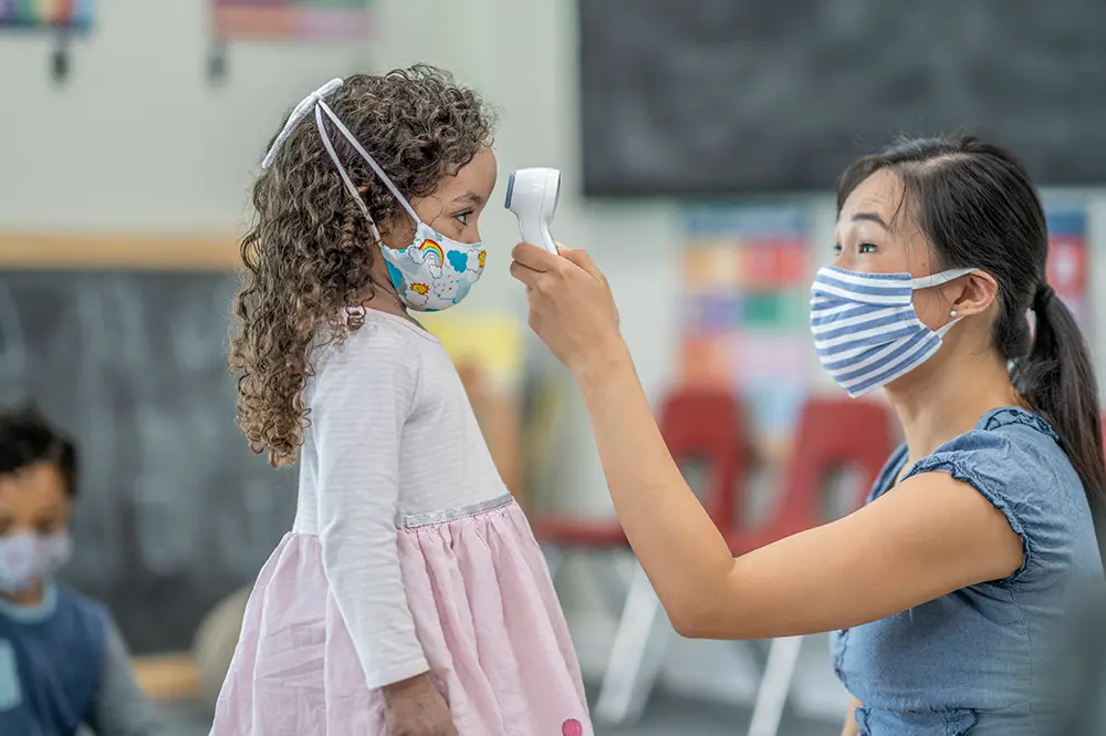 Child care provider testing a child's temperature