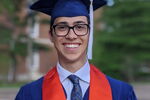 Recent graduate takes graduation photo on campus.