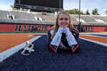 Student poses for photo in Marching Illini uniform on the field at Memorial Stadium