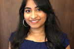 LAS student Sharon Abraham poses for photo in a blue dress against a wood background.