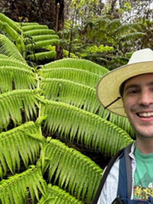 Max Christie in front of a green plant. 